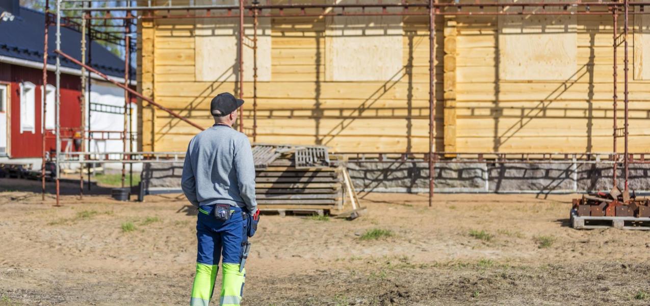 rakentaja talon edessä